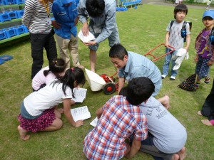 芝生のメンテナンスを当社スタッフから教わる児童